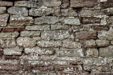 Eski bir taş duvarın yüzeyi, düzensiz yontulmuş taşlardan yapılmış bir taş..