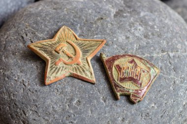 A red star from a military cap and a Komsomol badge, along with casings and bullets from a 7.62mm Mosin rifle, are artifacts of the Soviet Union. clipart