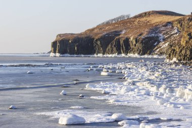 Rusya 'nın Vladivostok adasındaki Tobizin Burnu' nun kayalık kıyıları güneşli bir kış gününde kar ve yüzen buzla kaplıydı..