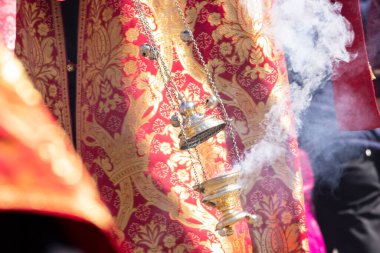 İşlemeli kilise cübbesindeki Ortodoks Hıristiyan bir rahibin elinde sigara içilen bir merkez..