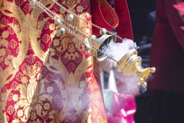 İşlemeli kilise cübbesindeki Ortodoks Hıristiyan bir rahibin elinde sigara içilen bir merkez..