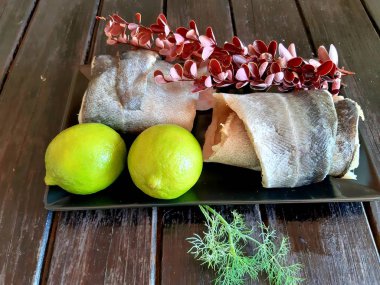 Fotoğrafta kireç, böğürtlen, biberiye, tuz ve baharat sprigs ile pollock balık taze bir fileto var.