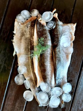 Bir tahta üzerinde taze balık pollock ve buz fileto.