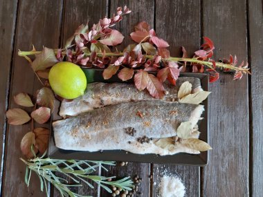 Fotoğrafta kireç, böğürtlen, biberiye, tuz ve baharat sprigs ile pollock balık taze bir fileto var.