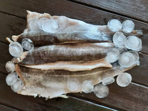Bir tahta üzerinde taze balık pollock ve buz fileto.