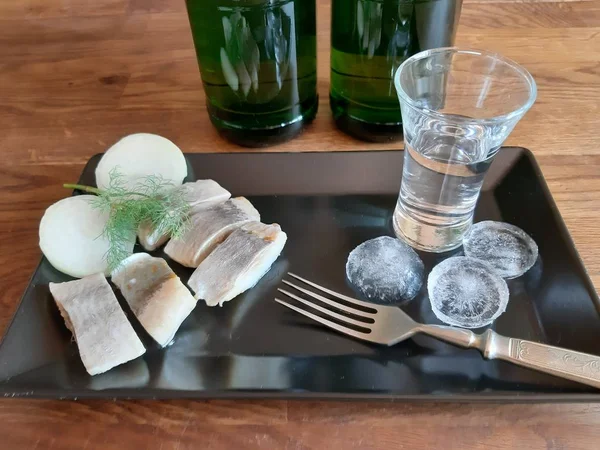 テーブルの上には 氷とウォッカのグラス ニシンと玉ねぎのサンドイッチがあります — ストック写真