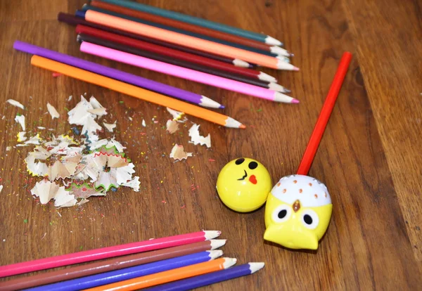 Multi-colored pencils. A child is sharpening pencils with a sharpener.