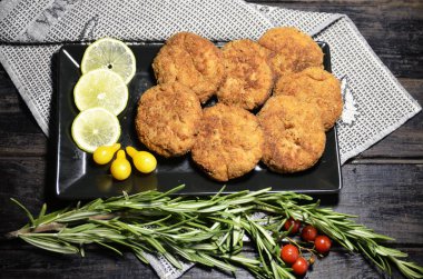 Ev mutfağı. Tabakta balık köftesi, limon dilimi, biberiye, vişneli domates var..