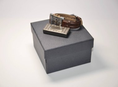 Beyaz arka planda, gri hediye kutusu, kol saati ve çakmak..