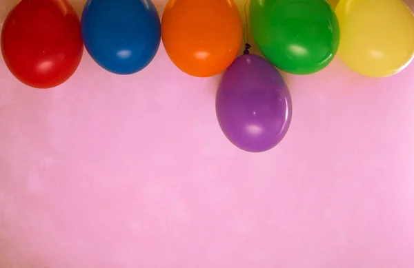 Pembe arka planda renkli balonlar. 