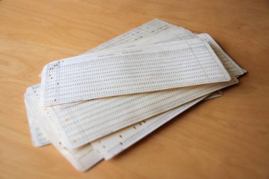 Fortran programı içeren delikli kartlar bir masaya yığılmış. Geçmiş bilgisayar kalıntısı. Bilgisayar programı kart parçaları dikdörtgen deliklerin konumu ile temsil. Vintage yazılım depolama.