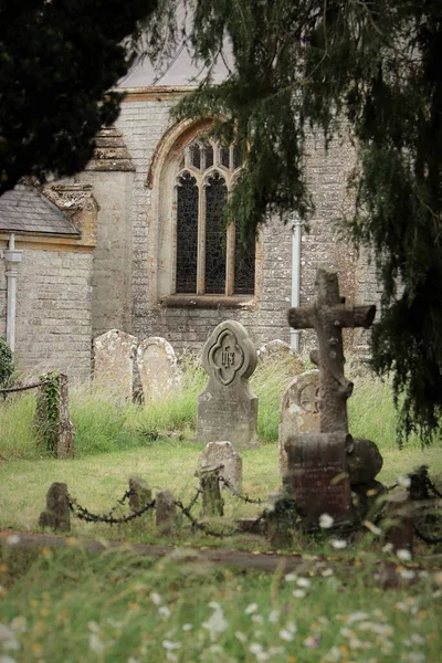 Church yard with grave stones and church window behind framed by trees