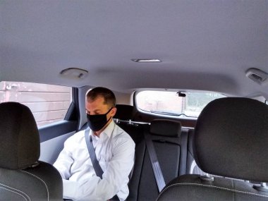 Taksinin arkasında maskeli bir adam var.