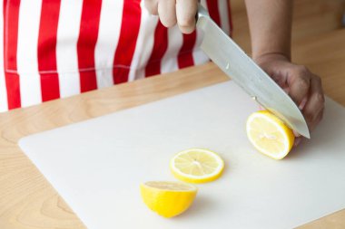 Kesik ve kaygan limon için bıçak kullanan el.