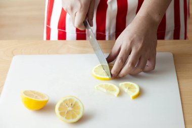 Kesik ve kaygan limon için bıçak kullanan el.