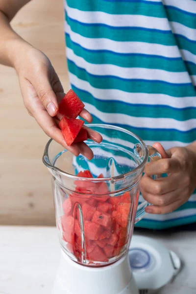 Hand put Watermelon cut in cube shape into food blender prepared for make juice