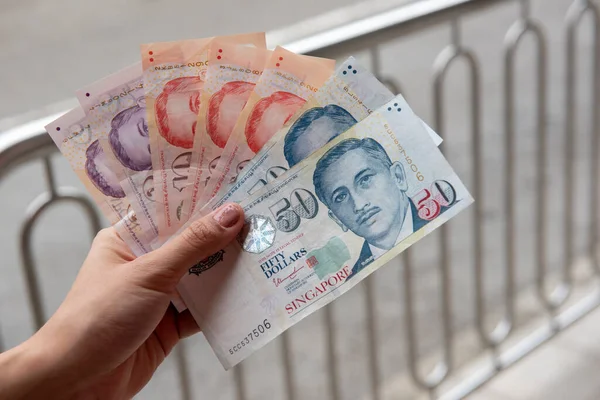 Hand holding Singapore dollar banknotes, currency exchange concept