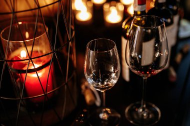 Bir sürü mumla süslenmiş boş şarap kadehlerini kapatın. Lüks restoranda karanlık atmospeher. Kutlama ve rahatlama kavramı.