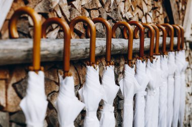 Düğün organizatörleri tarafından hazırlanmış ahşap saplı beyaz kapalı şemsiyeleri kapatın. Kutlama sırasında küçük ama önemli detaylar.