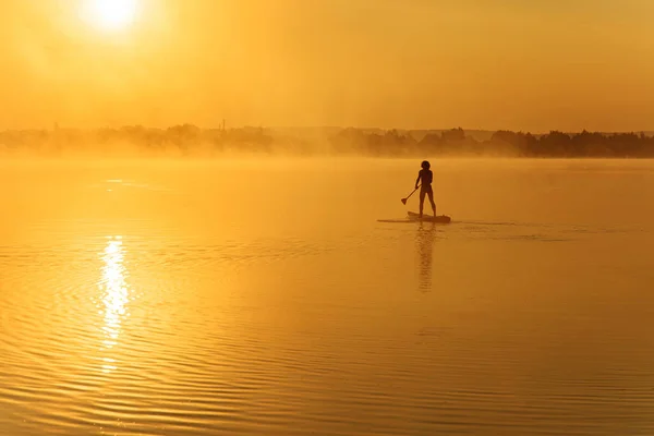Güçlü sağlıklı bir adam tek başına kürek tahtasında yüzüyor. — Stok fotoğraf