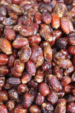 Meyvelerle çıkıyor. Bir dükkanda hurma yığını.