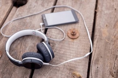 eski ahşap masa üzerinde gri kulaklık ile Smartphone