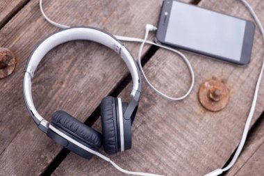 eski ahşap masa üzerinde gri kulaklık ile Smartphone