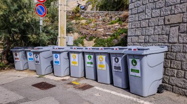 9 containers for sort rubbish and recycle are located on the street of small italian town. Environmental protection. September 17, 2024. Pomonte, Elba, Tuscany, Italy
