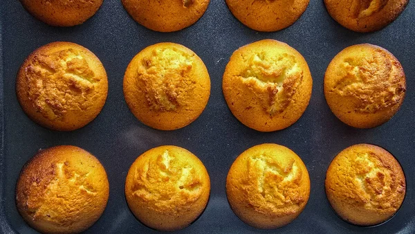 Top view of many appetizing homemade muffins in a black muffin tin. Easy baking