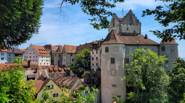 Meersburg Ortaçağ Şatosu manzarası ve güneşli bir günde mavi gökyüzünün arka planında eski kasabanın çatıları.