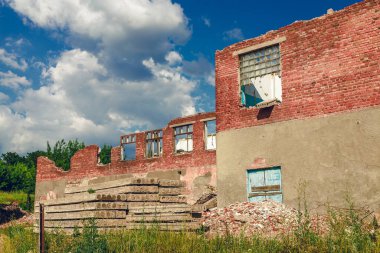 Eski kırmızı tuğla duvar. Kırık camlı eski püskü bir ev duvarı. Acil durum binasının çökme tehlikesi. Harap olmuş bir ev.