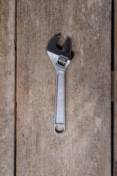 Adjustable Wrench tool on old wooden background. Top view