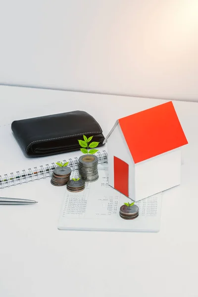 saving account passbook or financial statement, paper house model, Little tree and coins on office desk table. Business, finance, property ladder or mortgage loan concept