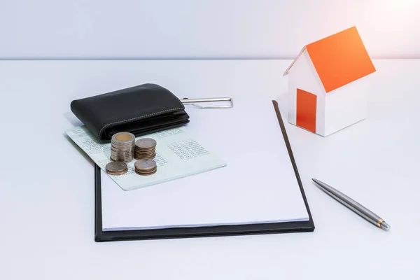 saving account passbook or financial statement, paper house model, and coins with Property Leasing Agreement on office desk table. Business, finance, property ladder or mortgage loan concept