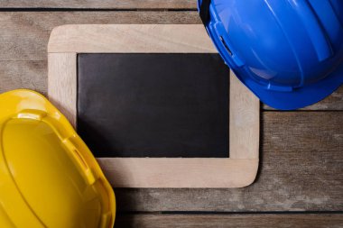 Sarı ve mavi koruyucu güvenlik kask ile eski ahşap arka plan kara tahta. Emanet ilk kavramlar