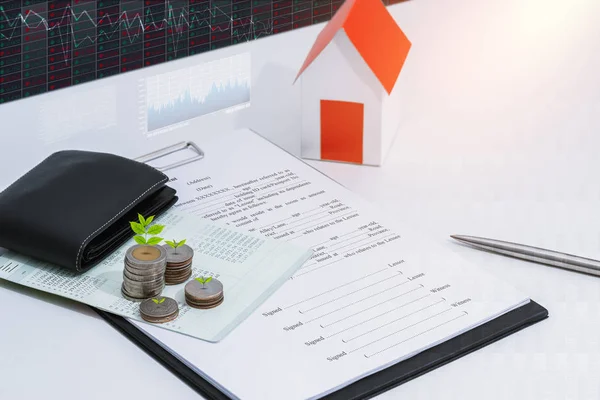 saving account passbook or financial statement, paper house model, Little tree and coins with Property Leasing Agreement on office desk table. Business, finance, property ladder or mortgage loan concept
