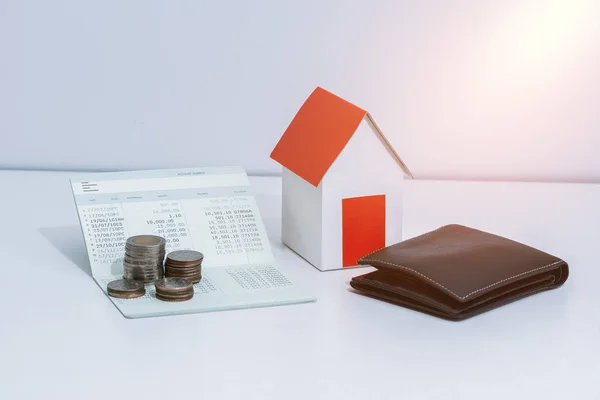 saving account passbook or financial statement, paper house model, and coins on office desk table. Business, finance, property ladder or mortgage loan concept