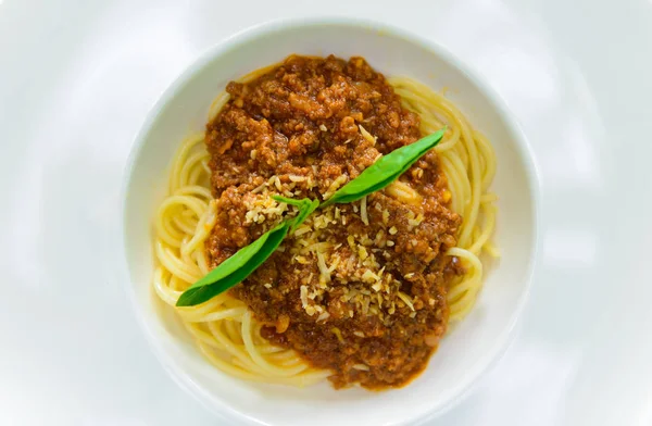 Beyaz tabak lezzetli lezzetli Bolognaise veya Bolognese spagetti sığır eti ve domates sosu süslenmiş parmesan peyniri ve fesleğen, üstten görünüm ile kıyılmış
