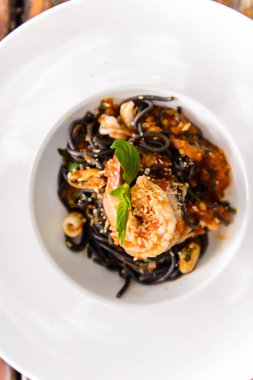 Ahşap masa üzerinde deniz ürünleri ile siyah spagetti üstten görünüm