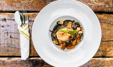 Ahşap masa üzerinde deniz ürünleri ile siyah spagetti üstten görünüm