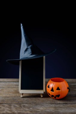 Cadılar Bayramı arka plan. kara tahta stand, ahşap zemin ve siyah arka plan üzerinde Halloween Pumpkins ile cadı şapka