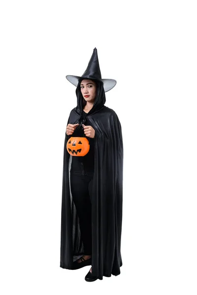 在黑色可怕的女巫万圣节服装的肖像站在帽子和持有一个南瓜孤立的白色背景与修剪路径 — 图库照片