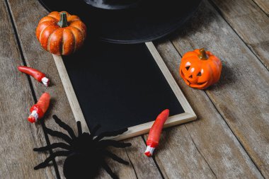 Halloween Pumpkins, cadı şapkası, Siyah örümcek ve ahşap zemin üzerinde boş yazı tahtası ile arka plan. yukarıdan görüntülemek