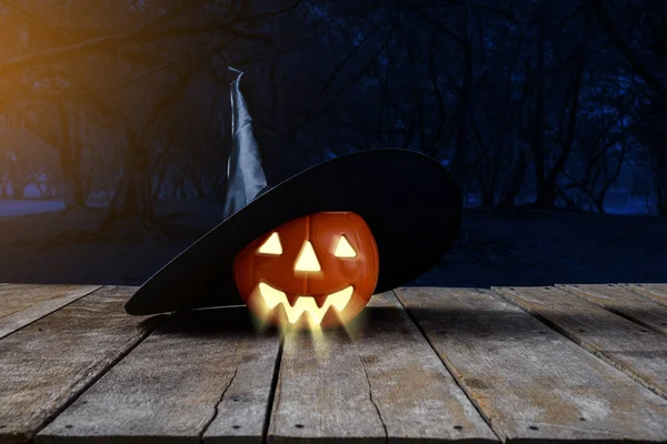 Halloween background. Spooky pumpkin, Witch hat on wooden floor with moon and dark forest. Halloween design with copyspace