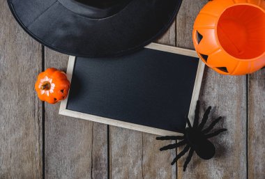 Halloween Pumpkins, cadı şapkası, Siyah örümcek ve ahşap zemin üzerinde boş yazı tahtası ile arka plan. yukarıdan görüntülemek