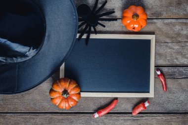 Halloween Pumpkins, cadı şapkası, Siyah örümcek ve ahşap zemin üzerinde boş yazı tahtası ile arka plan. yukarıdan görüntülemek