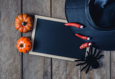 Halloween Pumpkins, cadı şapkası, Siyah örümcek ve ahşap zemin üzerinde boş yazı tahtası ile arka plan. yukarıdan görüntülemek