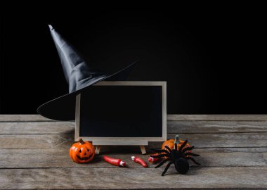 Cadılar Bayramı arka plan. standı, cadı şapkası, Siyah örümcek kara tahta ahşap zemin ve siyah arka plan üzerinde Halloween Pumpkins ile