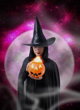 Portre siyah korku içinde kadın cadı halloween kılık Holding Cadılar Bayramı Balkabağı, sihirli ışıklar ve Cadılar Bayramı sanat tasarım arka plan ile büyük ay