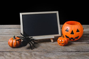 Cadılar Bayramı arka plan. Halloween Pumpkins, ahşap zemin ve siyah arka plan üzerinde siyah Örümcek Ayaklıklı kara tahta